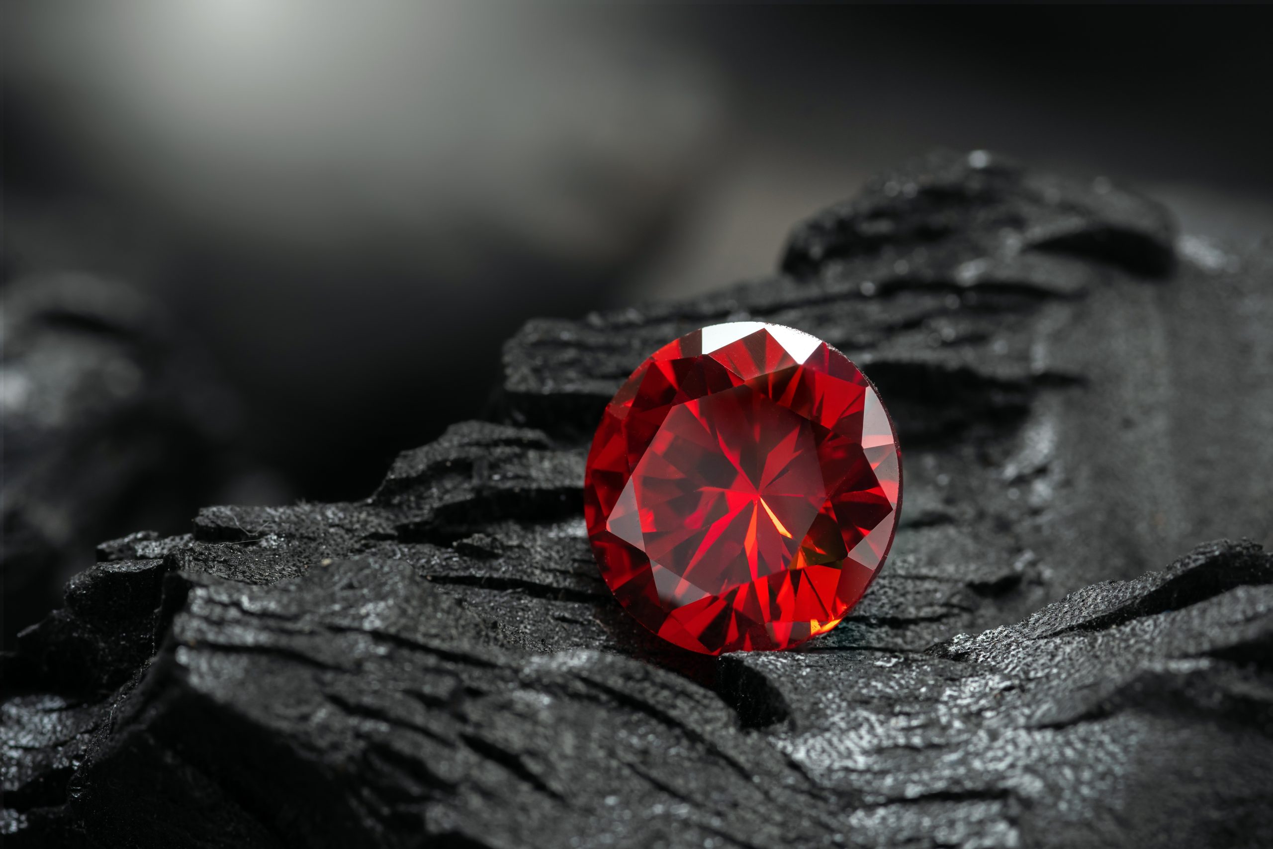 Red,Ruby,Gemstone,Round,Cut,On,Black,Coal,Background
